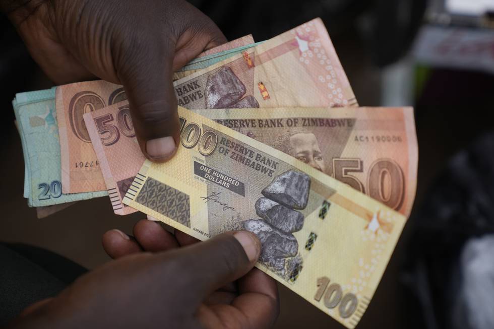 Bildet er av hender som holder ulike pengesedler fra Zimbabwe. Det er 20 dollar, 50 dollar og 100 dollar. Foto: Tsvangirayi Mukwazhi / AP / NTB