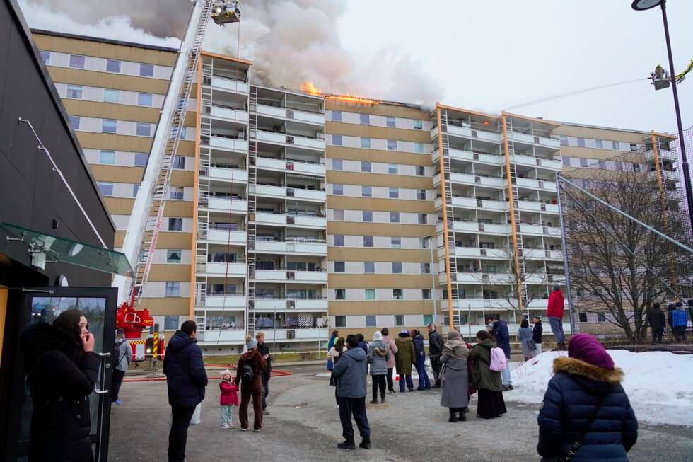 Bildet viser beboerne utenfor en boligblokk som brenner.
Foto: Terje Bendiksby / NTB