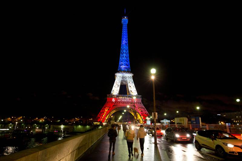Bildet viser Eiffel-tårnet med rødt, blått og hvitt lys. Det er fargene i det franske flagget.