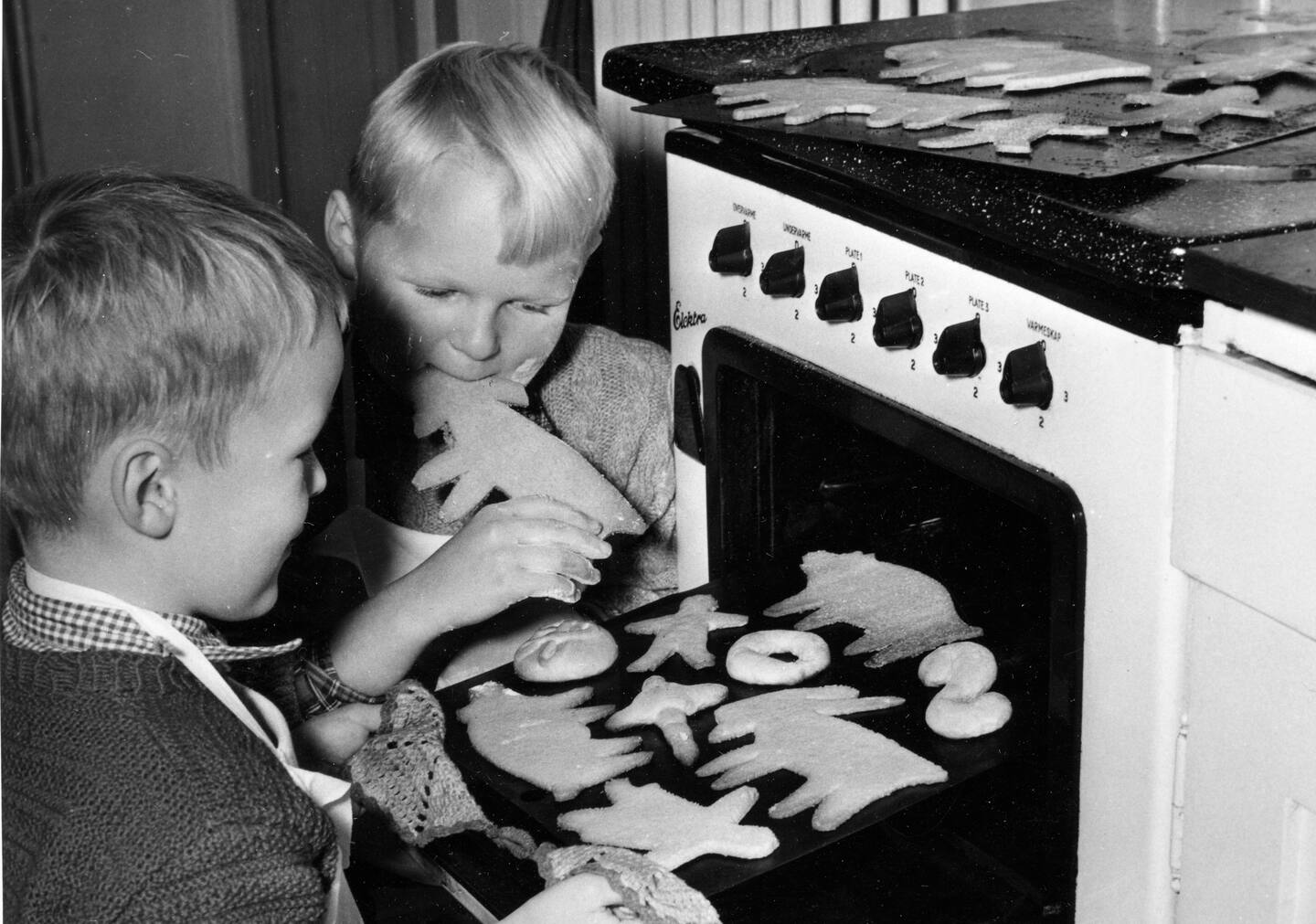 Bildet viser to gutter på 50-tallet som spiser pepperkaker. Foto: NTB