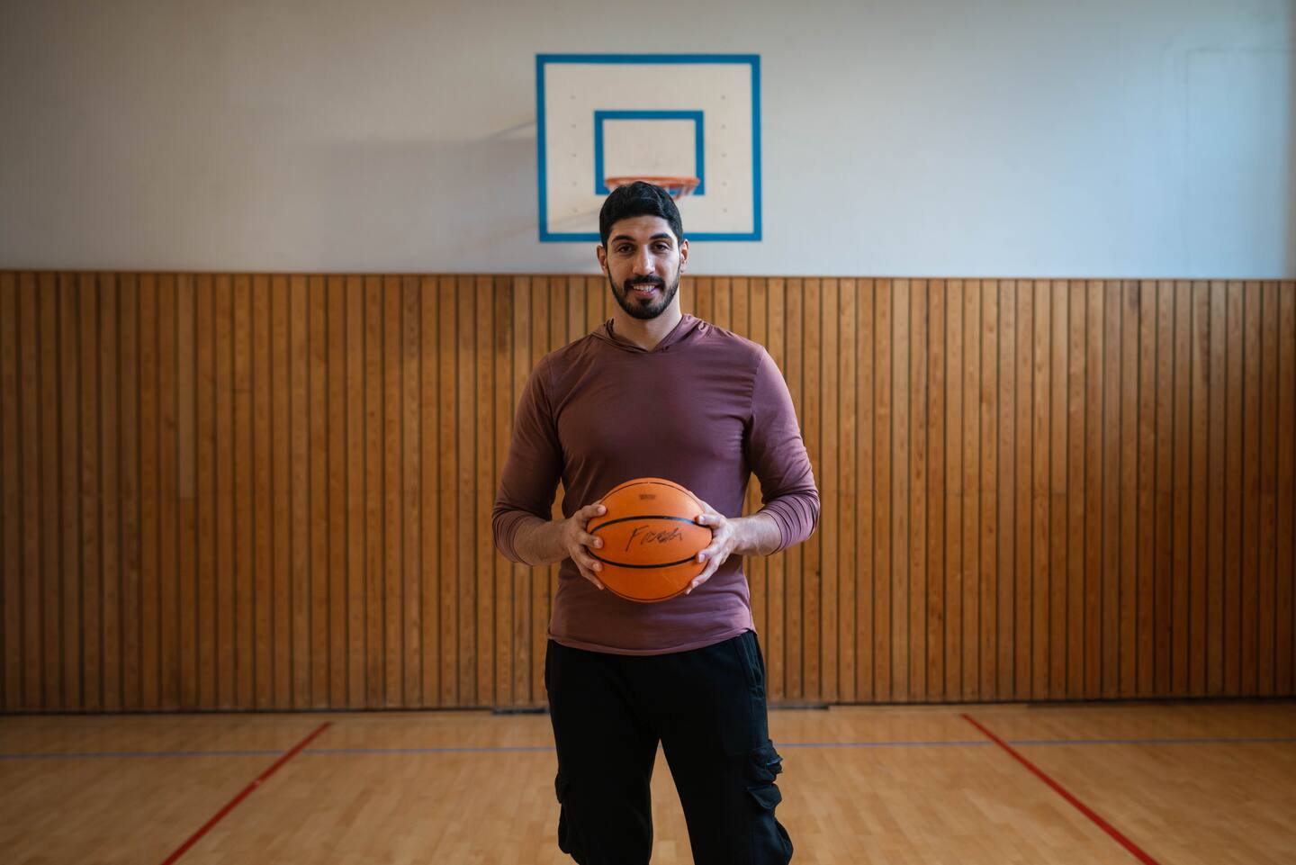 Bildet viser Enes Kanter Freedom med en basketball i en gymsal på Tøyen skole i Oslo. Foto: Anders Stensland Olsen