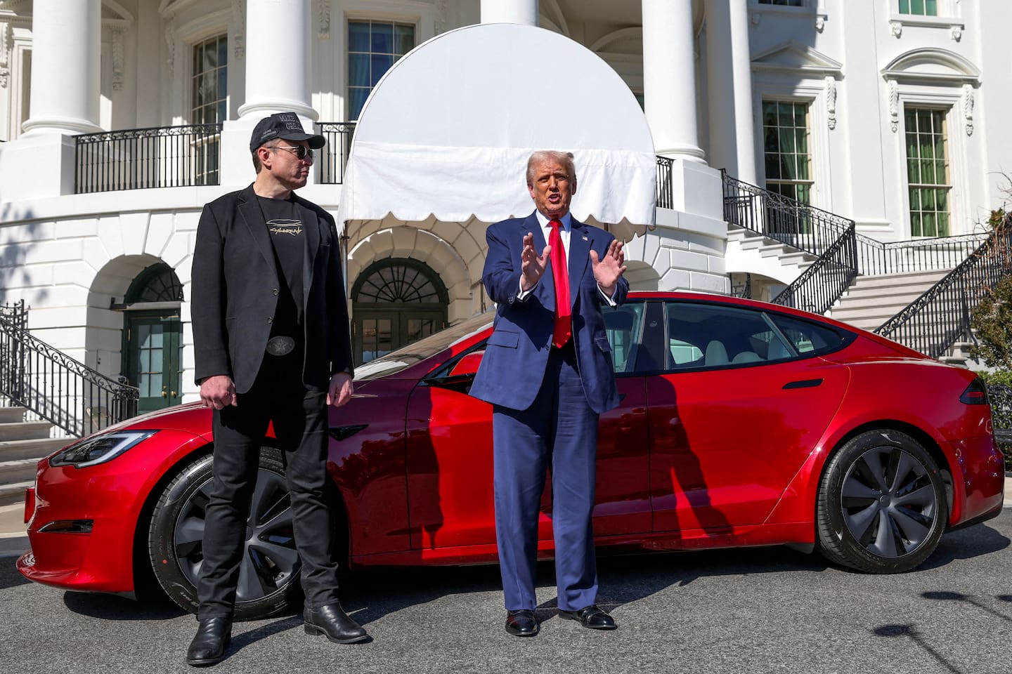 Bildet viser Elon Musk og Donald Trump med en Tesla i bakgrunnen. Foto: REUTERS / Kevin Lamarque / NTB