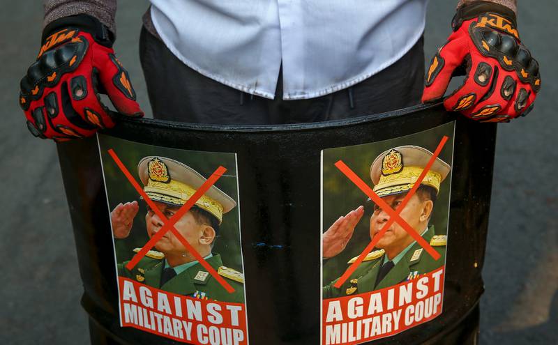 Bildet er av en demonstrant som holder opp plakater. Det er av general Min Aung Hlaing. Det er et rødt kryss over ham. Under står det at folk er mot at militæret tok makta i Myanmar.