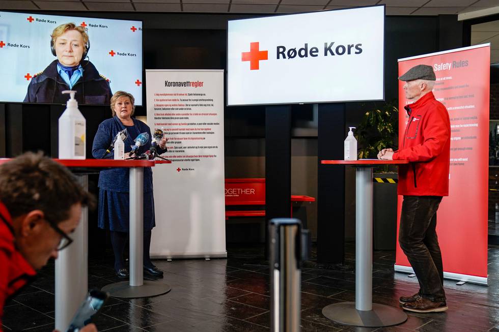 Bildet er fra en pressekonferanse. Der deltok statsminister Erna Solberg og Røde Kors-president Robert Mood. På skjerm bakgrunnen er Kjersti Løvik. Hun er leder i landsrådet i Røde Kors Hjelpekorps. Hun deltok på videolink.