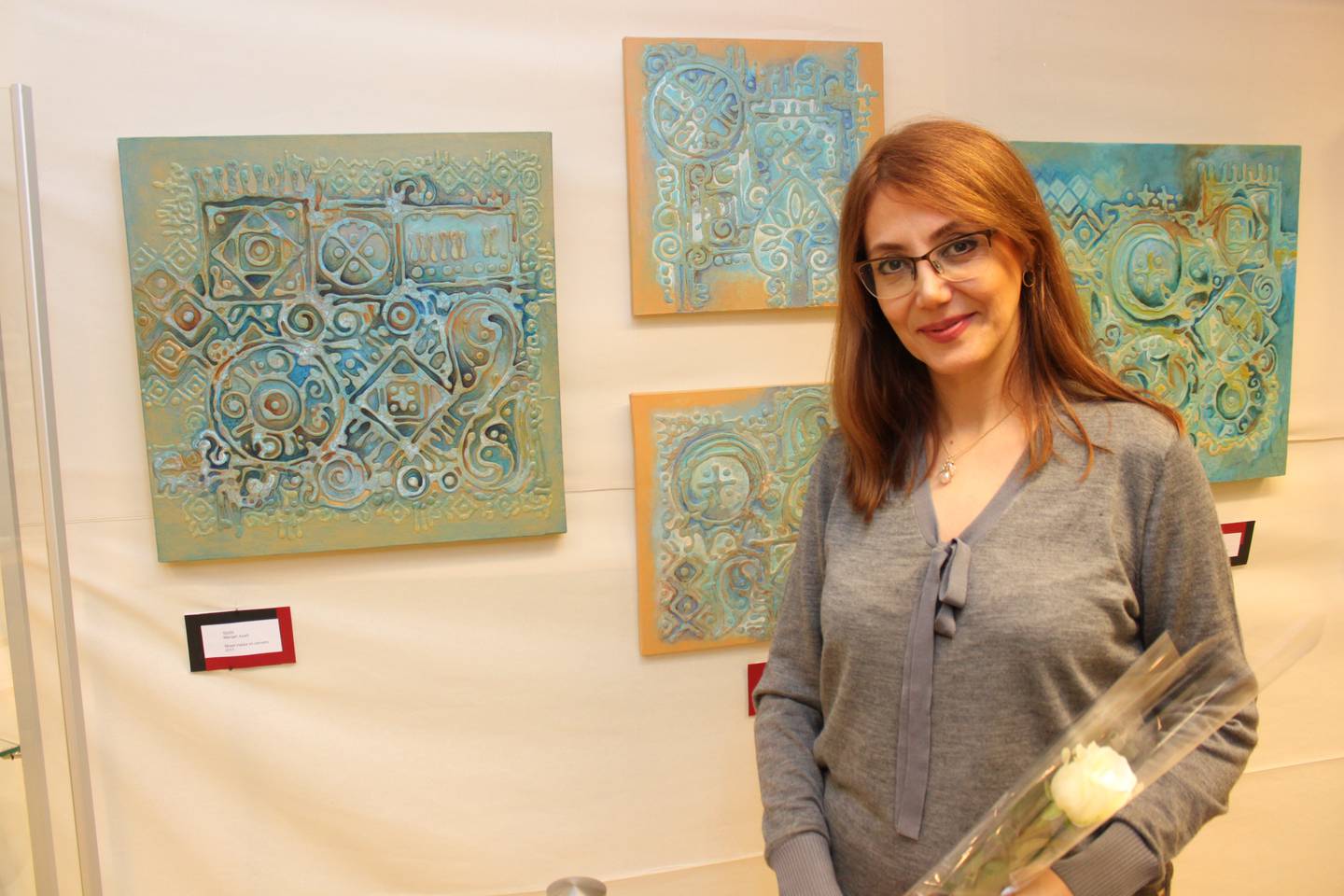Bildet viser kunstneren Manijeh Azadi. Hun har laget bilder som synes i bakgrunnen.  I tillegg har hun vært med og oversatt bøker fra norsk til persisk.