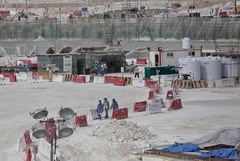 Bildet er av en byggeplass i Qatar. Det går arbeidsfolk langs en oppmerket rute inne på byggeplassen.