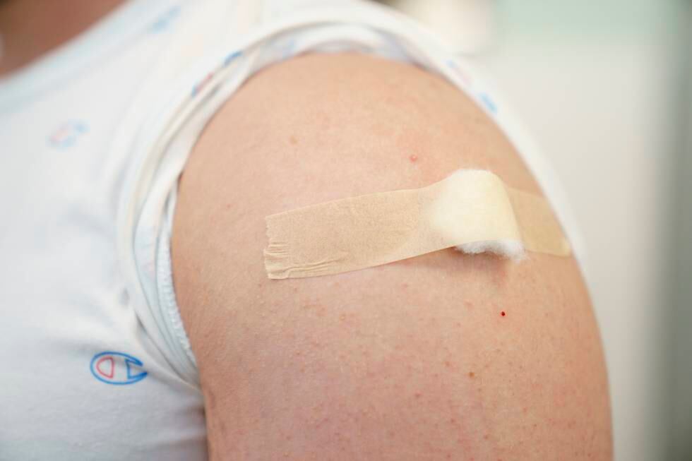 Bildet er av en arm, med en bomullsdott med teip over. Den er satt på overarmen der det er satt en vaksine mot korona. Ermet på den hvite t-skjorta er rullet opp. Foto: Torstein Bøe / NTB