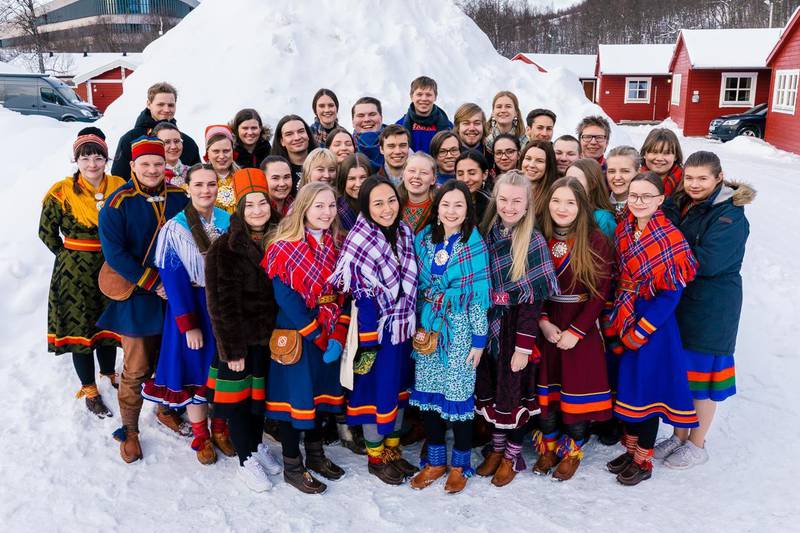Bildet er av en gruppe samiske ungdommer. Det er fra landsmøtet i organisasjonen Noereh. De står ute i snøen. De har på kofter i mange ulike farger.