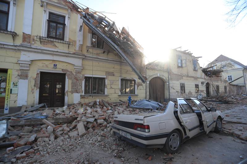 Bildet er av en ødelagt bygning og en ødelagt bil i byen Petrinja.