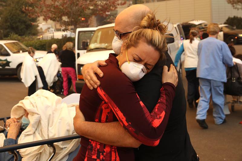 Bildet viser folk som omfavner hverandre utenfor et sykehus.