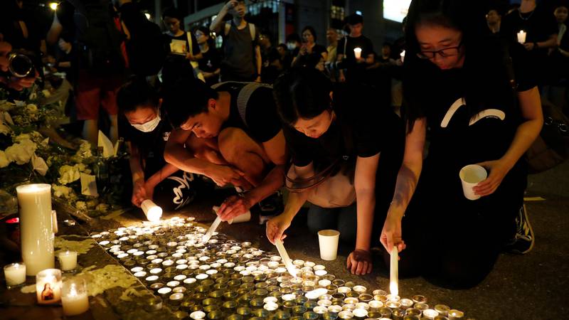 Bildet viser demonstranter som tenner lys for en mann som døde.