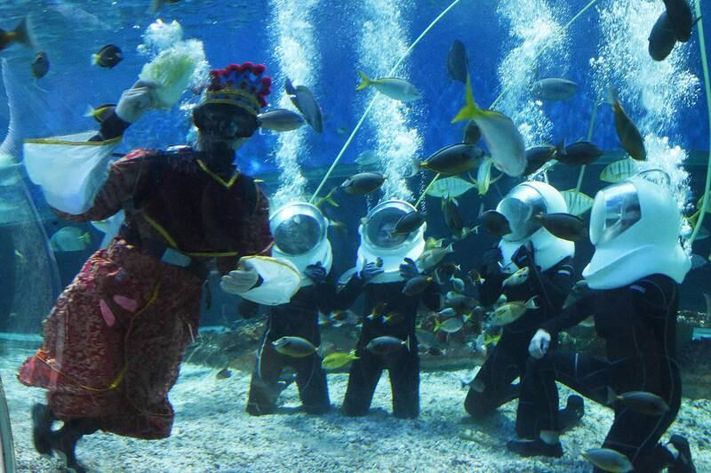 Filippinene: En dykker kledd som en kinesisk gud for velstand, mater fiskene. Det skjer i et gedigent akvarium i Manila på Filippinene. 