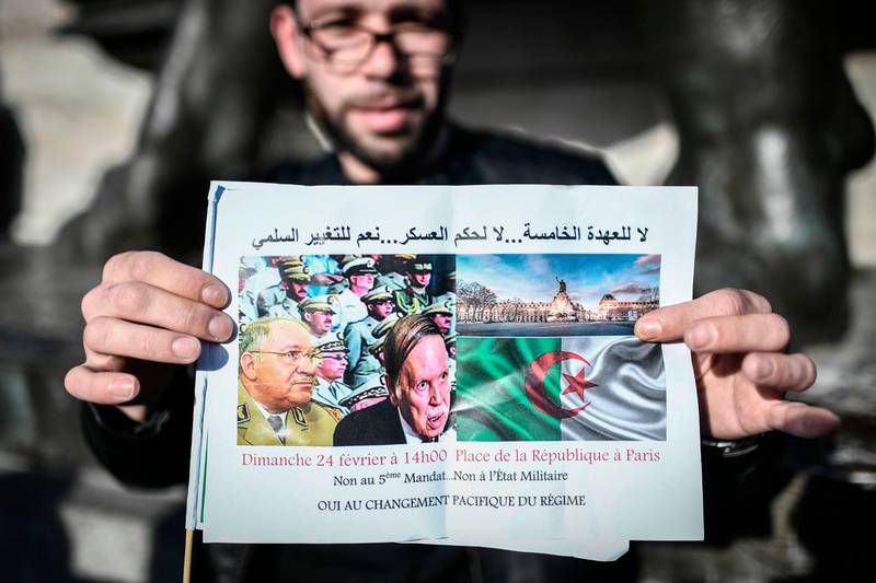 Bildet viser en mann som holder opp et bilde med tekst mot presidenten i Algerie.