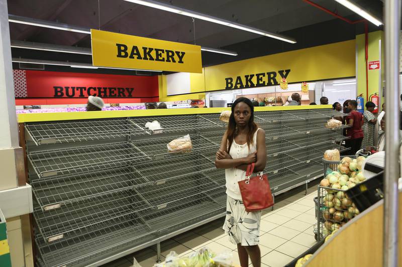 Bildet viser en kvinne ved tomme butikkhyller i Zimbabwe.